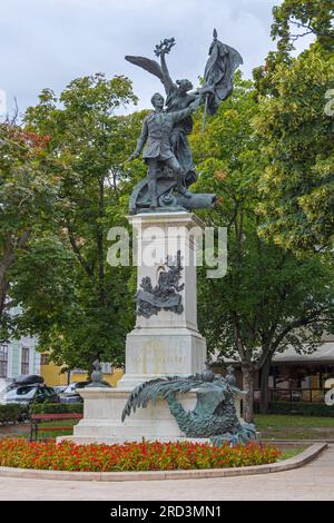 Budapest, Ungheria - 31 luglio 2022: Monumento a Szabad Hazaert statua di bronzo del soldato con corona d'alloro della vittoria alata e Freedo bandiera nazionale Foto Stock