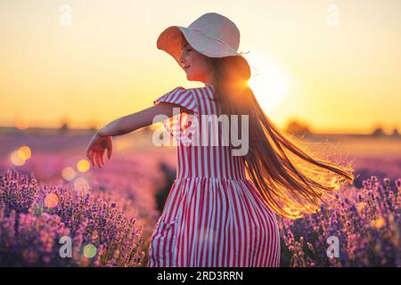 Campo di lavanda e bouquet di fiori. Bella donna con vestito e cappello che si gode le file di lavanda colorate Foto Stock