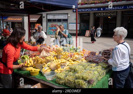 Due giorni prima delle elezioni politiche suppletive, i residenti acquistano frutta e verdura fuori dalla stazione della metropolitana di Uxbridge, il 18 luglio 2023, a Londra, in Inghilterra. Il collegio di Uxbridge and South Ruislip è una delle tre elezioni suppletive locali che si sono tenute lo stesso giorno, ma Uxbridge è stato rappresentato in parlamento dall'ex primo ministro conservatore Boris Johnson per otto anni prima di dimettersi da deputato. Il 20 luglio sarà contestato da 17 candidati. Foto Stock