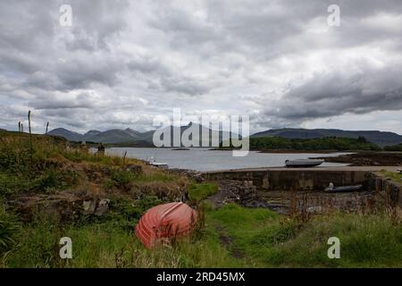 Montagne di Mull Beinn Mhòr, Beinn Fahda, Beinn nan Gabhar e Beinn Ghraig dall'isola di Ulva, isola di Mull con una barca rossa rovesciata in primo piano. Foto Stock