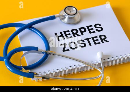 Stetoscopio medico, taccuino bianco con l'iscrizione Herpes zoster, sfondo giallo, herpes zoster, una malattia della pelle che si sviluppa come risultato del r Foto Stock