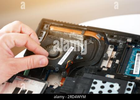 Fissaggio del computer portatile. Il riparatore trattiene la ventola di raffreddamento e le riparazioni da surriscaldamento. Disassemblaggio del computer, sostituzione, rimozione di polvere e sporcizia nell'impianto di raffreddamento su no Foto Stock