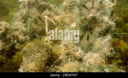 La rete da pesca perduta si trova sui fondali marini nelle alghe verdi Ulva nelle giornate di sole splendenti nel Mar Nero, inquinamento da fantasmi di mari e oceani, Mar Nero Foto Stock