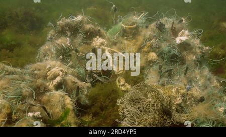 La rete da pesca perduta si trova sui fondali marini nelle alghe verdi Ulva nelle giornate di sole splendenti nel Mar Nero, inquinamento da fantasmi di mari e oceani, Mar Nero Foto Stock