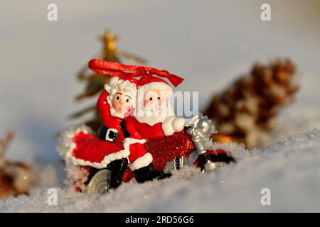 Decorazioni natalizie, Babbo Natale e la signora Claus cavalcano sulla neve in moto Foto Stock