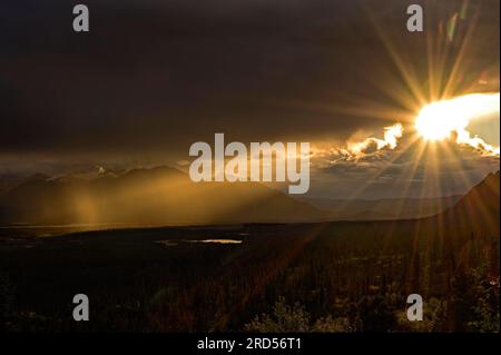 Il sole di sera si apre attraverso la fitta copertura nuvolosa nel paesaggio subartico della tundra, Denali Highway, Alaska, USA Foto Stock