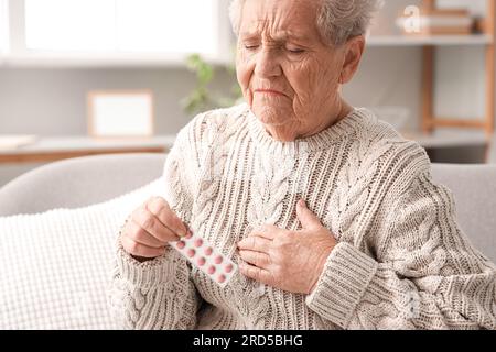Donna anziana con pillole che ha un attacco di cuore a casa Foto Stock