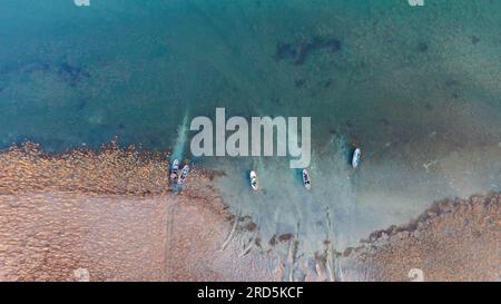 Barche da pesca sulla riva ghiacciata del lago. Foto Stock