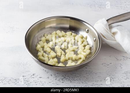 Padella con pera stufata nel burro su sfondo azzurro. Cucinare risotto fatto in casa con pera e gorgonzola, passo dopo passo, passo 1. Foto Stock