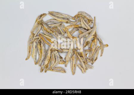 Acciughe secche su sfondo bianco. Isolato. Сlose-up. Vista dall'alto. Piccole acciughe secche su sale sul tavolo. Pesce di mare salato per la birra. Frutti di mare Foto Stock