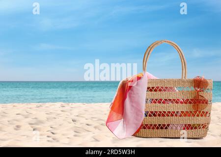 Borsa con accessori sulla soleggiata spiaggia oceanica, spazio per testo. Vacanze estive Foto Stock