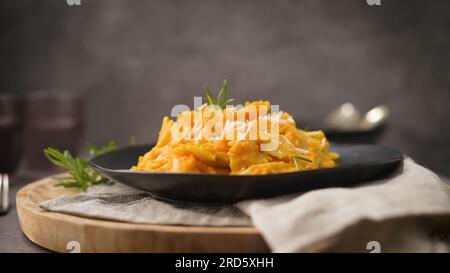 FARFALLE pasta con salsa di zucca in un piatto di ceramica su un piano cucina in pietra scura. Foto Stock