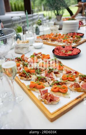 Bruschette, formaggio con salsicce, paté. Un tavolo festivo per una compagnia di persone con molti piatti diversi. Foto verticale Foto Stock
