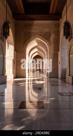 Un corridoio magicamente illuminato alla grande Moschea del Sultano Qaboos a Mascate, Oman. Foto Stock