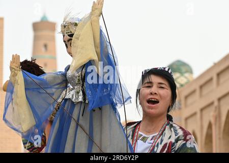 Donna uzbeka che tiene un burattino durante una performance per strada a Khiva, Uzbekistan Foto Stock