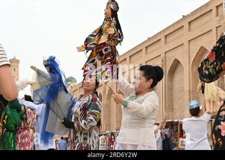 Donna uzbeka che tiene un burattino durante una performance per strada a Khiva, Uzbekistan Foto Stock