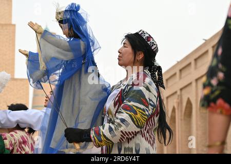 Donna uzbeka che tiene un burattino durante una performance per strada a Khiva, Uzbekistan Foto Stock