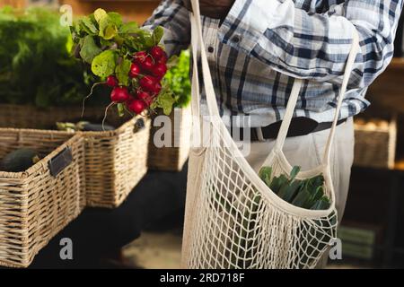 Senior afro-americano che tiene il ravanello, che fa shopping al negozio di alimentari biologico di alimenti salutari Foto Stock