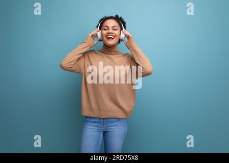sfondo isolato, giovane bruna, freelance ispanica che ascolta musica con le cuffie bluetooth Foto Stock