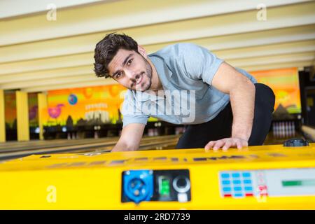 uomo che prende la palla da bowling dal rack del club Foto Stock