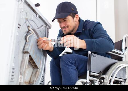 disabilitato idraulico che ripara la lavatrice Foto Stock