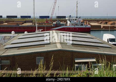 Pannelli solari sul tetto del magazzino nei moli di Shoreham Harbour, West Sussex, Inghilterra. Con l'acciaieria dietro. Niente persone. Nessun logo. Foto Stock