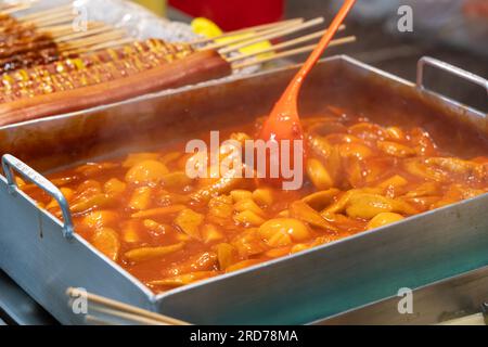 Deliziosa cucina coreana Tteokbokki, gustosa torta di riso speziata con salsicce, uova al mercato per spuntini di Street food. Foto Stock