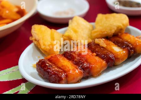 Deliziosa cucina coreana Tteokbokki, gustosa torta di riso speziata con salsicce, uova al mercato per spuntini di Street food. Foto Stock