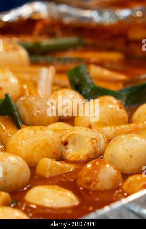 Deliziosa cucina coreana Tteokbokki, gustosa torta di riso speziata con salsicce, uova al mercato per spuntini di Street food. Foto Stock