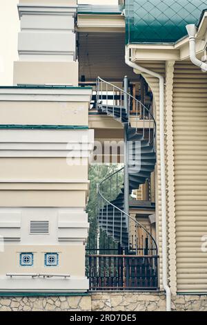 Moderna scala a chiocciola. Sfondo astratto dell'architettura moderna. Primo piano di una bella scala esterna a chiocciola in ferro battuto sul lato dell'edificio. Foto di alta qualità Foto Stock