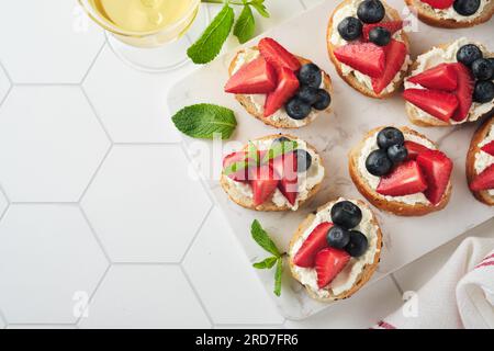 Panino con bandiera americana con fragole, mirtilli, panna dolce montata, formaggio morbido su pane tostato. 4 luglio cibo per il giorno dell'indipendenza americana. In Foto Stock