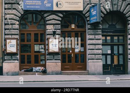 Un uomo visto dormire davanti al centro culturale. In Ungheria, soprattutto a Budapest, si è diffusa una preoccupazione per i senzatetto. A causa dell'elevata inflazione, la città ha visto un aumento del numero di persone che vivono nelle strade. Fattori come la povertà, la disoccupazione, problemi di salute mentale e la mancanza di alloggi a prezzi accessibili contribuiscono al problema. Il governo ungherese e le autorità locali hanno attuato varie misure per affrontare i senzatetto. Questi includono la fornitura di rifugi di emergenza, servizi sociali e programmi volti al reinserimento nella società. Non governativo Foto Stock