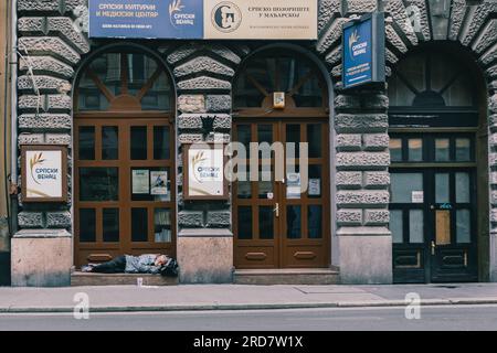 13 giugno 2023, Budapest, Ungheria: Un uomo visto dormire davanti al centro culturale. In Ungheria, soprattutto a Budapest, si è diffusa una preoccupazione per i senzatetto. A causa dell'elevata inflazione, la città ha visto un aumento del numero di persone che vivono nelle strade. Fattori come la povertà, la disoccupazione, problemi di salute mentale e la mancanza di alloggi a prezzi accessibili contribuiscono al problema. Il governo ungherese e le autorità locali hanno attuato varie misure per affrontare i senzatetto. Questi includono la fornitura di rifugi di emergenza, servizi sociali e programmi rivolti a reintegr Foto Stock