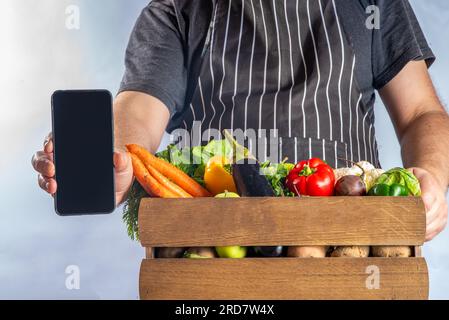 Concetto di shopping del mercato biologico agricolo, scatola di legno con estate, verdure crude e frutta autunnali, mani contadine su sfondo bianco Foto Stock