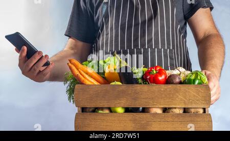 Concetto di shopping del mercato biologico agricolo, scatola di legno con estate, verdure crude e frutta autunnali, mani contadine su sfondo bianco Foto Stock