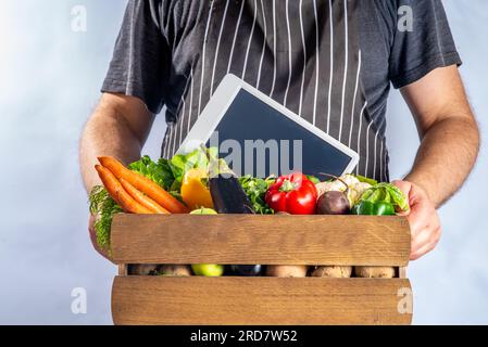 Concetto di shopping del mercato biologico agricolo, scatola di legno con estate, verdure crude e frutta autunnali, mani contadine su sfondo bianco Foto Stock