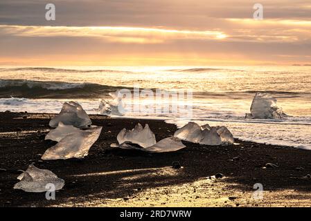 Paesaggio mozzafiato con scintillanti blocchi di ghiaccio arenati sulla sabbia nera di Diamond Beach, Breiðamerkursandur all'alba, Islanda Foto Stock