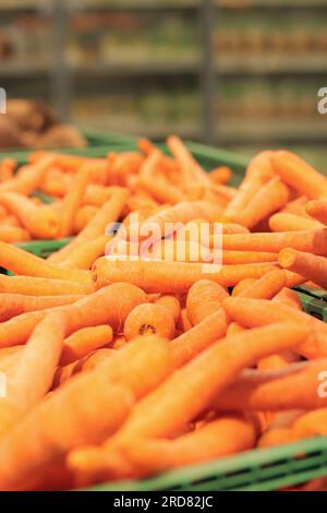 Vendita di carote lavate in scatole di plastica. Vendita di carote, messa a fuoco selettiva. Verdure in un supermercato da vicino, vista laterale Foto Stock