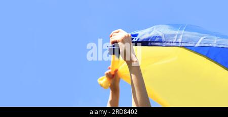 Bandiera gialla e blu dell'Ucraina nelle mani della donna. Bandiera blu e gialla sventolante dell'Ucraina sullo sfondo del cielo. Celebra Constitution Indepe Foto Stock