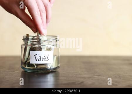 Salvadanaio con dollari per viaggiare. Vaso di vetro con soldi. La donna mette più soldi nel salvadanaio. Messa a fuoco selettiva Foto Stock