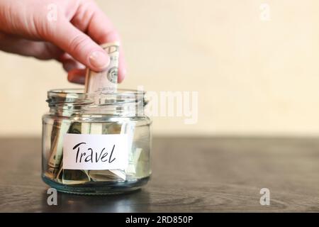 Salvadanaio con dollari per viaggiare. Vaso di vetro con soldi. La donna mette più soldi nel salvadanaio. Messa a fuoco selettiva Foto Stock