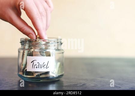 Salvadanaio con dollari per viaggiare. Vaso di vetro con soldi. La donna mette più soldi nel salvadanaio. Messa a fuoco selettiva Foto Stock