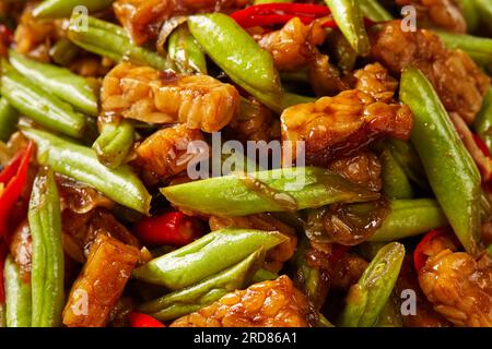 una porzione di tempeh saltato in padella e fagioli verdi Foto Stock