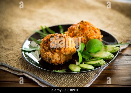Polpette cotte in un piatto con verdure fresche, su un tavolo di legno. Foto Stock