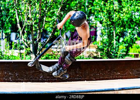 Giovane che pratica lo Scootering (Freestyle Scootering) nel nuovo Skatepark del parco centrale di Igualada, Barcellona, Spagna Foto Stock