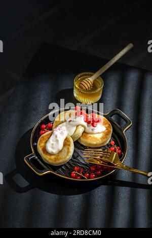cheesecake al formaggio cottage con frutti di bosco e panna acida su sfondo nero Foto Stock