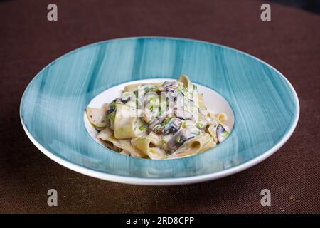 pasta con funghi e salsa in un piatto blu. Foto Stock