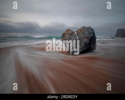 Lunga esposizione del mare che scorre e di una roccia a forma di cuore sulla spiaggia di Portizuelo, Asturie, Spagna, Europa Foto Stock