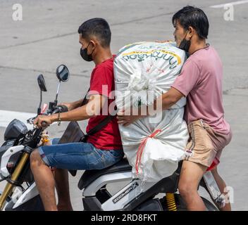 SAMUT PRAKAN, THAILANDIA, 10 febbraio 2023, due uomini stanno trasportando un grosso carico su una moto Foto Stock