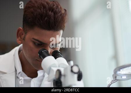 Serio ingegnere indiano che sta indagando sul microscopio Foto Stock